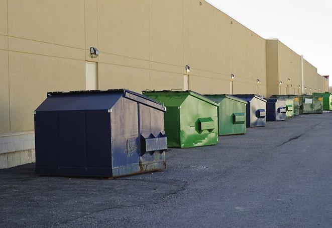 tilted front-load dumpsters being emptied by waste management workers in Dryden, NY